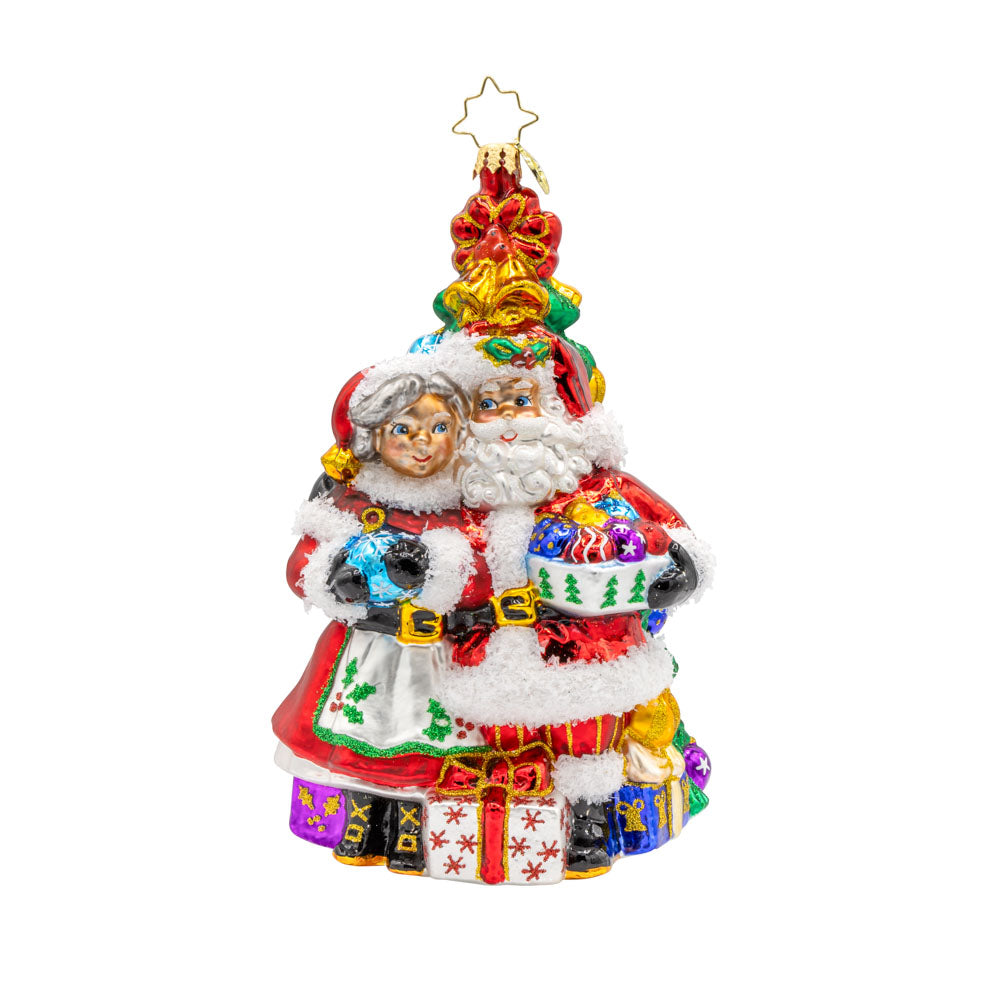 Holiday Harmony ornament. Santa and Mrs. Claus are decorating the tree with tinsel and trimmings. View of front. 