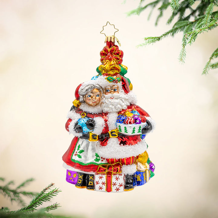 Holiday Harmony ornament. Santa and Mrs. Claus are decorating the tree with tinsel and trimmings. View of front. 