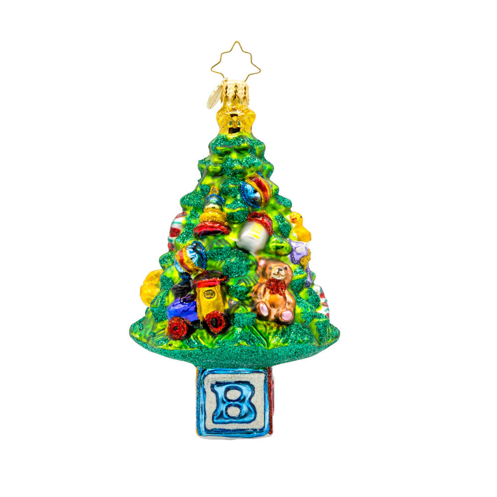 Bundle of Joy Spruce ornament. This piece features a decorated Christmas tree and a collection of baby-themed toys. View of front.