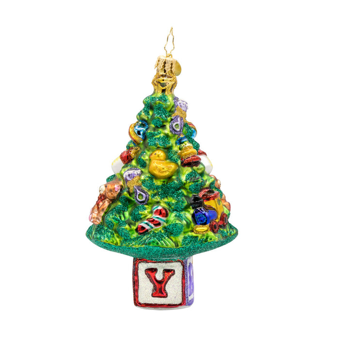 Bundle of Joy Spruce ornament. This piece features a decorated Christmas tree and a collection of baby-themed toys. View of right side.