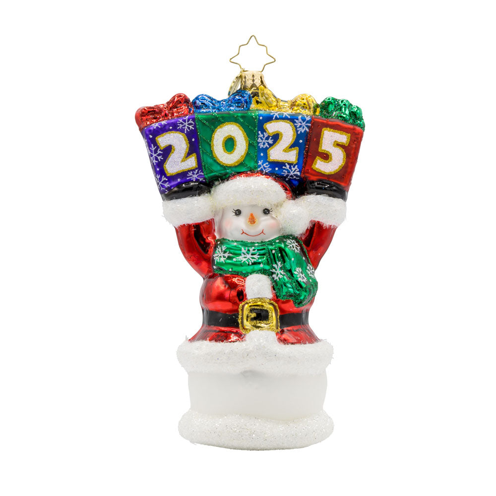 2025 Snowman Greetings ornament. A snowman dressed as Santa raises a stack of gifts dated "2025" above his head. View of front. 