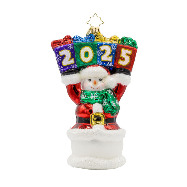 2025 Snowman Greetings ornament. A snowman dressed as Santa raises a stack of gifts dated "2025" above his head. View of front. 