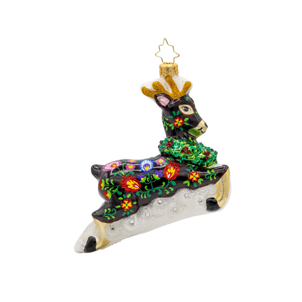 Enchanted Elegance ornament. This festive reindeer ornament features shiny antlers, a holly wreath around its neck, and playful leap. View of left side.