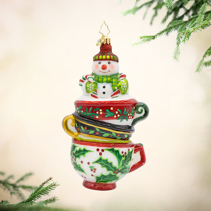 Teatime Treasures Ornament. Featuring a charming snowman nestled snugly inside a whimsical stack of teacups. View of front.