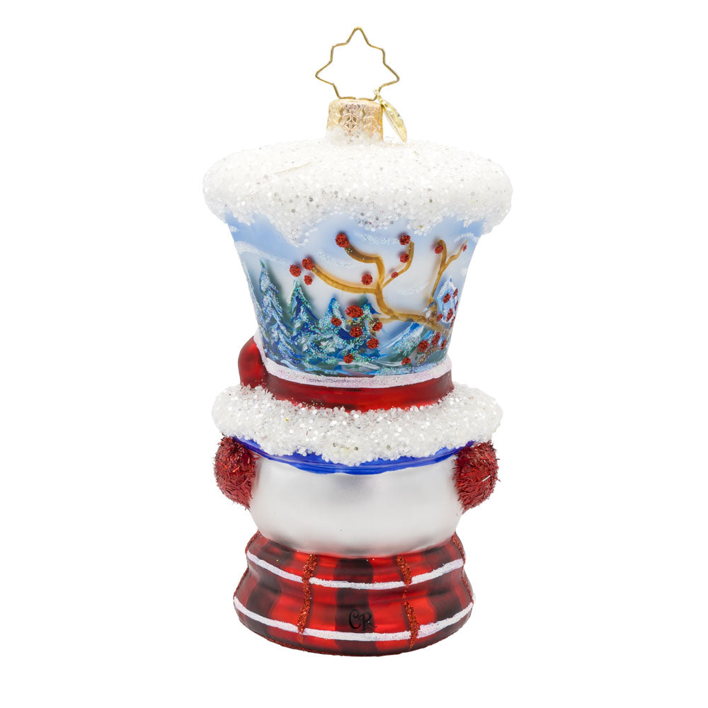 Snowy and the Cardinals ornament. This snowman ornament features a hand-painted winter scene, complete with a cozy cabin, a vibrant cardinal, and a snowy landscape. He wears a festive hat, topped with a snowy peak, sparkling glitter muffs and satin scarf. View of back.
