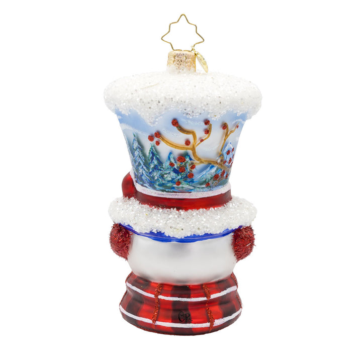 Snowy and the Cardinals ornament. This snowman ornament features a hand-painted winter scene, complete with a cozy cabin, a vibrant cardinal, and a snowy landscape. He wears a festive hat, topped with a snowy peak, sparkling glitter muffs and satin scarf. View of back.