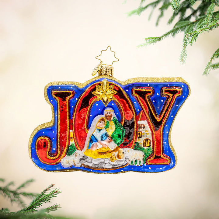 Holy Harmony ornament. Nativity scene with detailed figures of Mary, Joseph, baby Jesus, and the three wise men, shimmering star, and the word "JOY" shining brightly. View of front. 