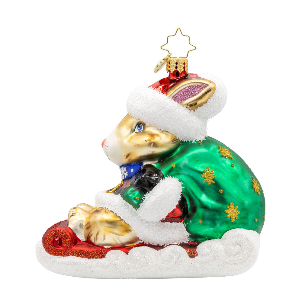 Healing Holiday Hare ornament. A rabbit donning a green cloak and red hat sits on a sleigh. View of front. 