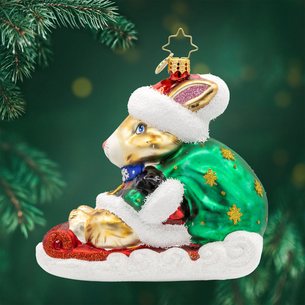 Healing Holiday Hare ornament. A rabbit donning a green cloak and red hat sits on a sleigh. View of front. 