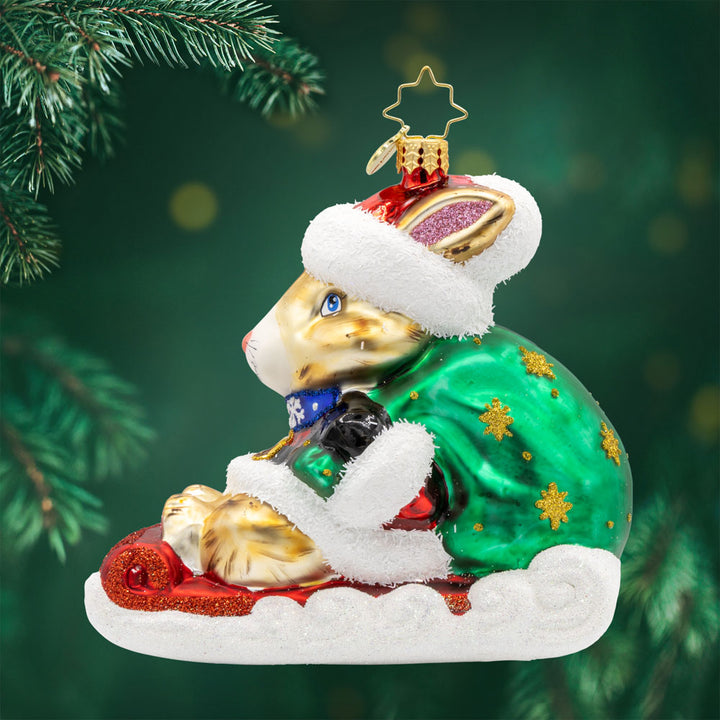 Healing Holiday Hare ornament. A rabbit donning a green cloak and red hat sits on a sleigh. View of front. 