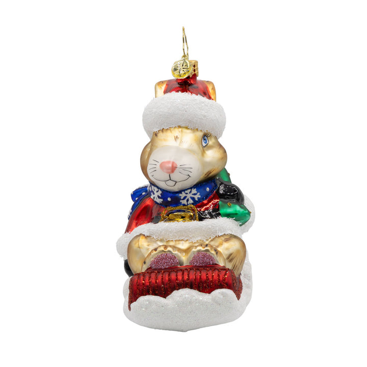 Healing Holiday Hare ornament. A rabbit donning a green cloak and red hat sits on a sleigh. View of left side.