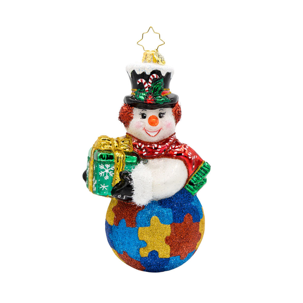 Puzzle Piece Pal ornament. This snowman is carrying a gift. His bottom half is painted to look like a jigsaw puzzle. View of front. 