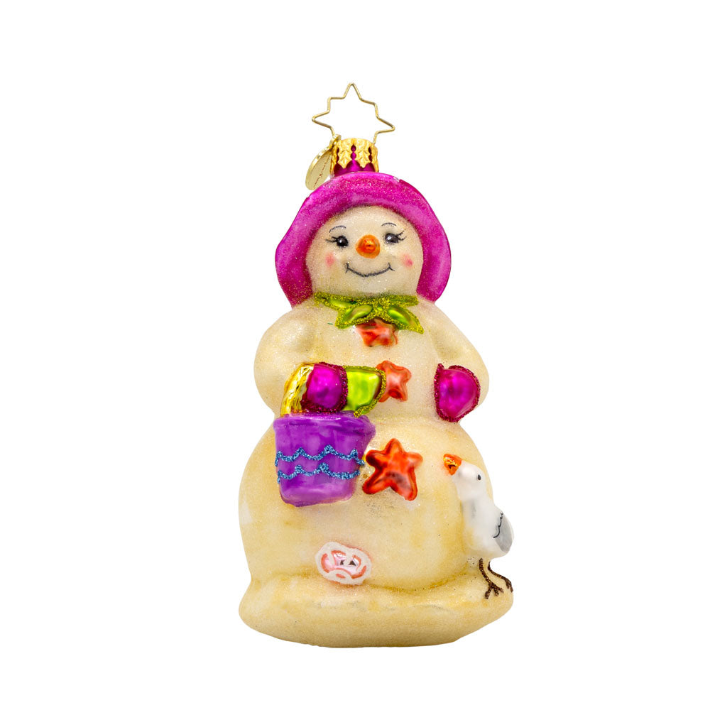 Coastal Chiller ornament. Sun-kissed snowman with a pink bucket, mittens, and flowered sun hat. Starfish buttons and a seagull friend in tow. View of front. 