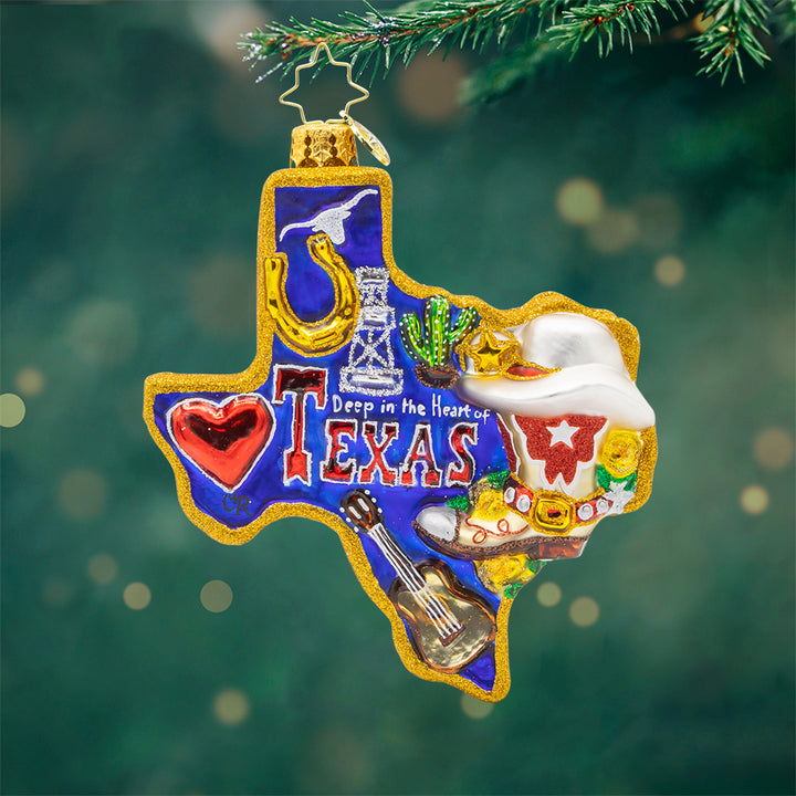 Lone Star Pride ornament. Shaped like the great state itself, the glittering blue, white, and red of the Texas flag on the back to the golden horseshoe and oil rig, every detail tells a story of Texan pride. View of front. 