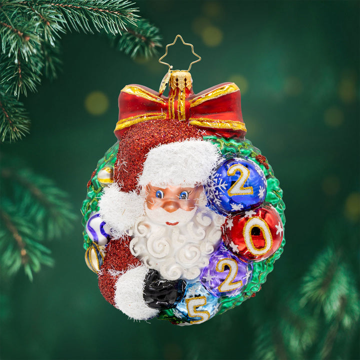 Smiling Through 2025 ornament. Santa is encircled by a Christmas wreath. Ornament balls are dated with "2025." View of front.