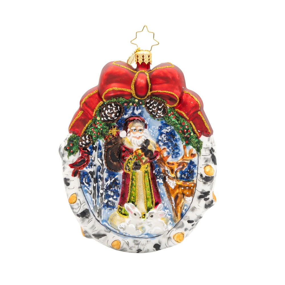 Winter Wonderland Wanderer ornament. Santa and his furry friends explore a snowy wonderland. This scene is framed by a wreath. View of front. 