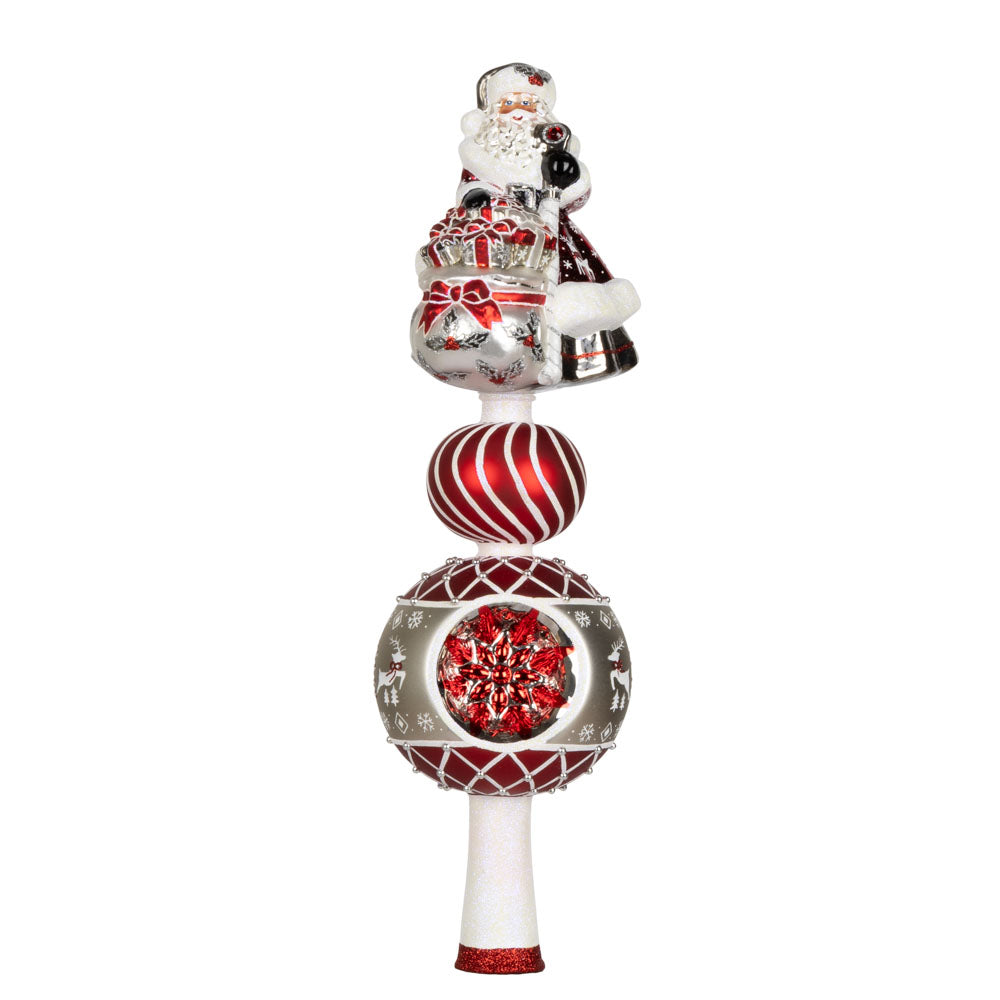This enchanting finial features Santa, with his rosy cheeks, snowy beard, and a sack full of gifts above two decorated rounds. View of front.