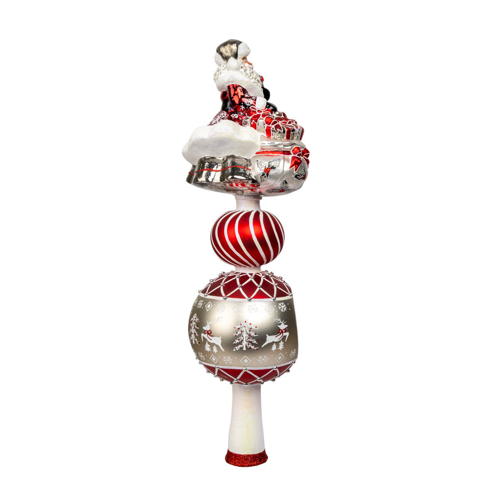 This enchanting finial features Santa, with his rosy cheeks, snowy beard, and a sack full of gifts above two decorated rounds. View of left side.