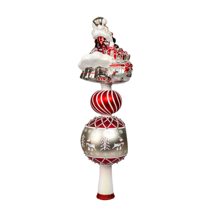 This enchanting finial features Santa, with his rosy cheeks, snowy beard, and a sack full of gifts above two decorated rounds. View of left side.