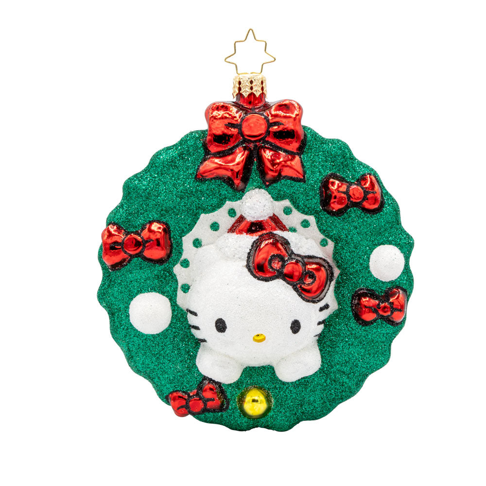 Hello Kitty's Holiday Wreath ornament. Hello Kitty wears her signature red bow nestled in a festive wreath adorned with red bows, holly, and sparkly accents. View of front. 