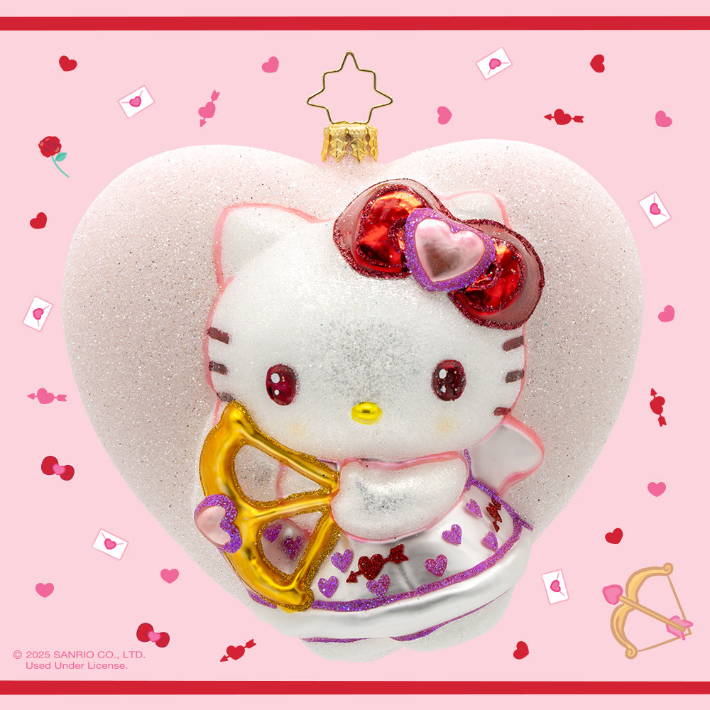 Hello Kitty Sweetheart ornament. Dressed as a Cupid, complete with a bow and arrow, she's surrounded by hearts and glitter. View of front. 