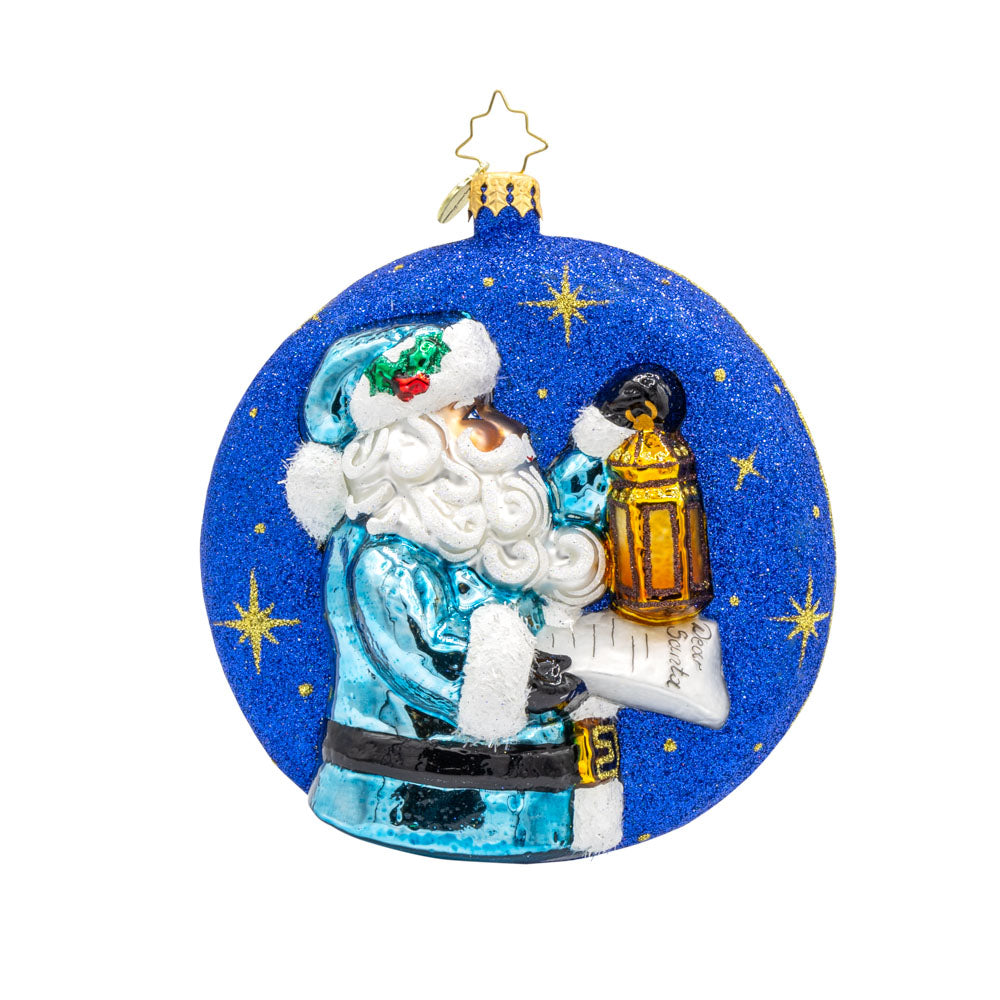 Santa's Guiding Light ornament. Santa wears blue, a "Dear Santa" letter in hand and lantern in the other walking through a starry night. View of front. 