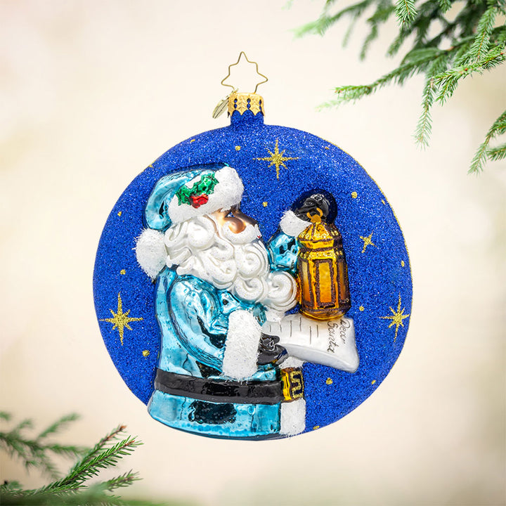 Santa's Guiding Light ornament. Santa wears blue, a "Dear Santa" letter in hand and lantern in the other walking through a starry night. View of front. 