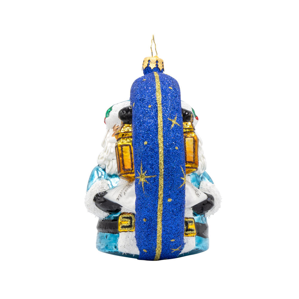 Santa's Guiding Light ornament. Santa wears blue, a "Dear Santa" letter in hand and lantern in the other walking through a starry night. View of right side.