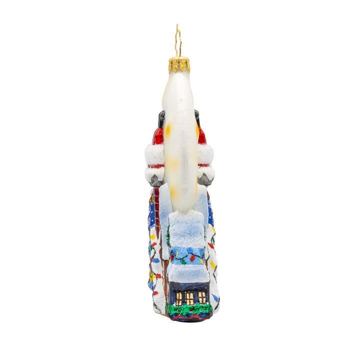 Santa's Moonlight Mischief ornament. Santa goes headfirst down a chimney a set a scene of festive homes lit by a large moon. View of right side.