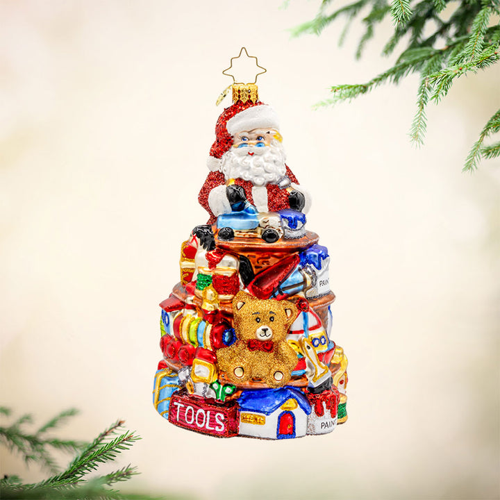 NorthPole Workshop Ornament. Santa atop a pile of toys. View of front.