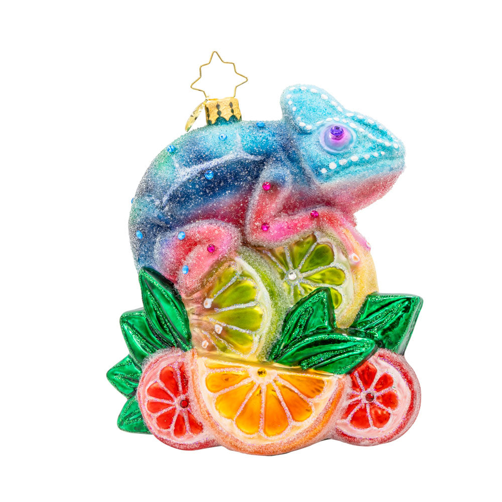 Camouflage Cutie ornament. A chameleon is perched on a vibrant pile of fruit. View of left side.