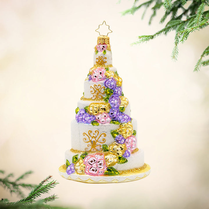 A Taste of Love ornament. An elegant wedding cake with an array of flowers and intricate designs. View of front.  