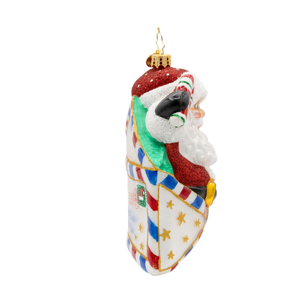 Letters To Santa ornament. Santa is featured here popping out of an envelope covered in gold stars, with a candy cane in his hand. View of left side.