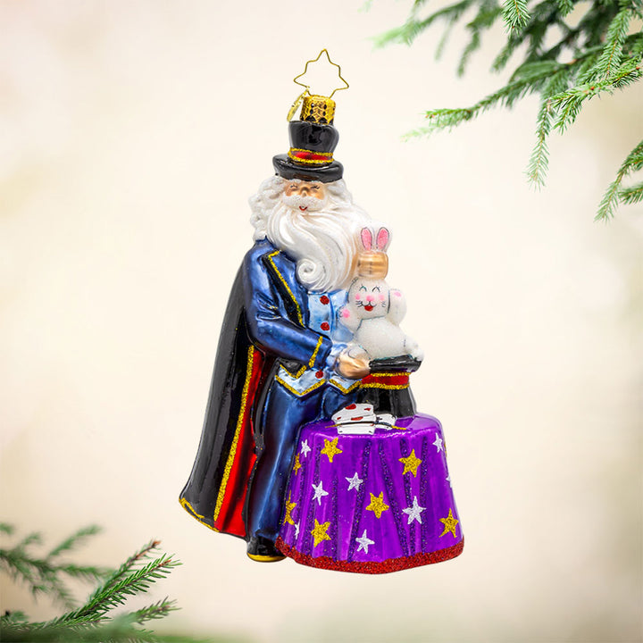 The Merry Magician ornament. Santa features a fluffy beard and cape as he pulls a rabbit out of his sparkling hat. View of front. 