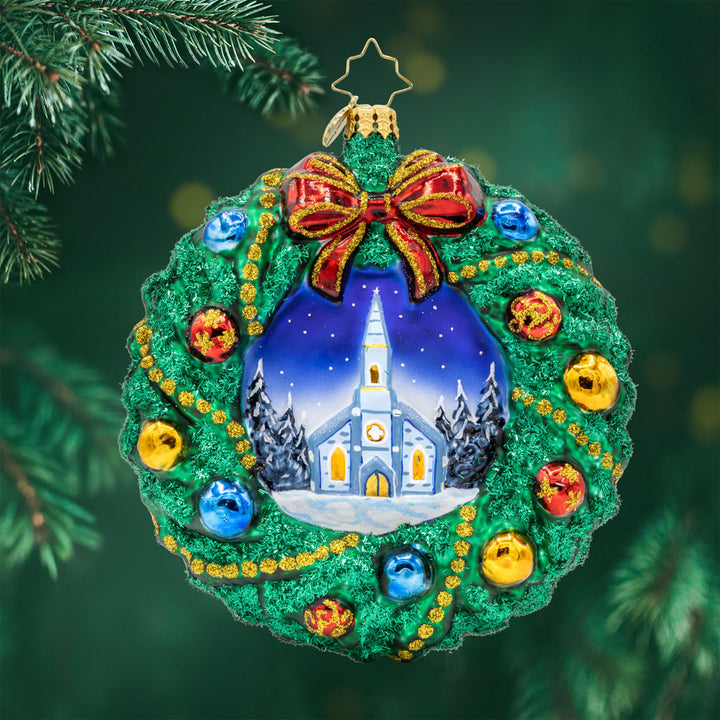 Sacred Harmony Wreath ornament. An elegantly designed wreath, showcasing a charming church in the center. View of front. 