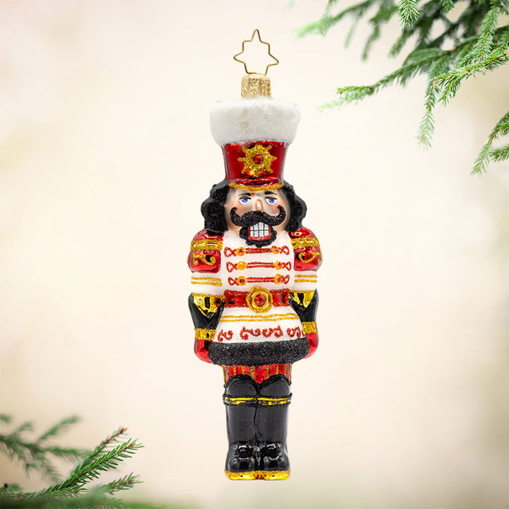 Gemstone Guardian ornament. This nutcracker wears a satin white jacket adorned with red gems and shiny black boots. View of front. 