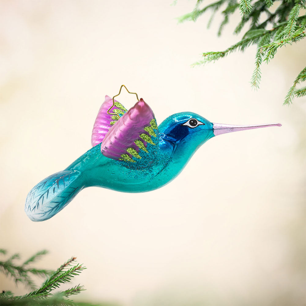 This Hummingbird Christmas ornament showcases a dazzling hummingbird with iridescent blue and fuchsia plumage. View of left side.