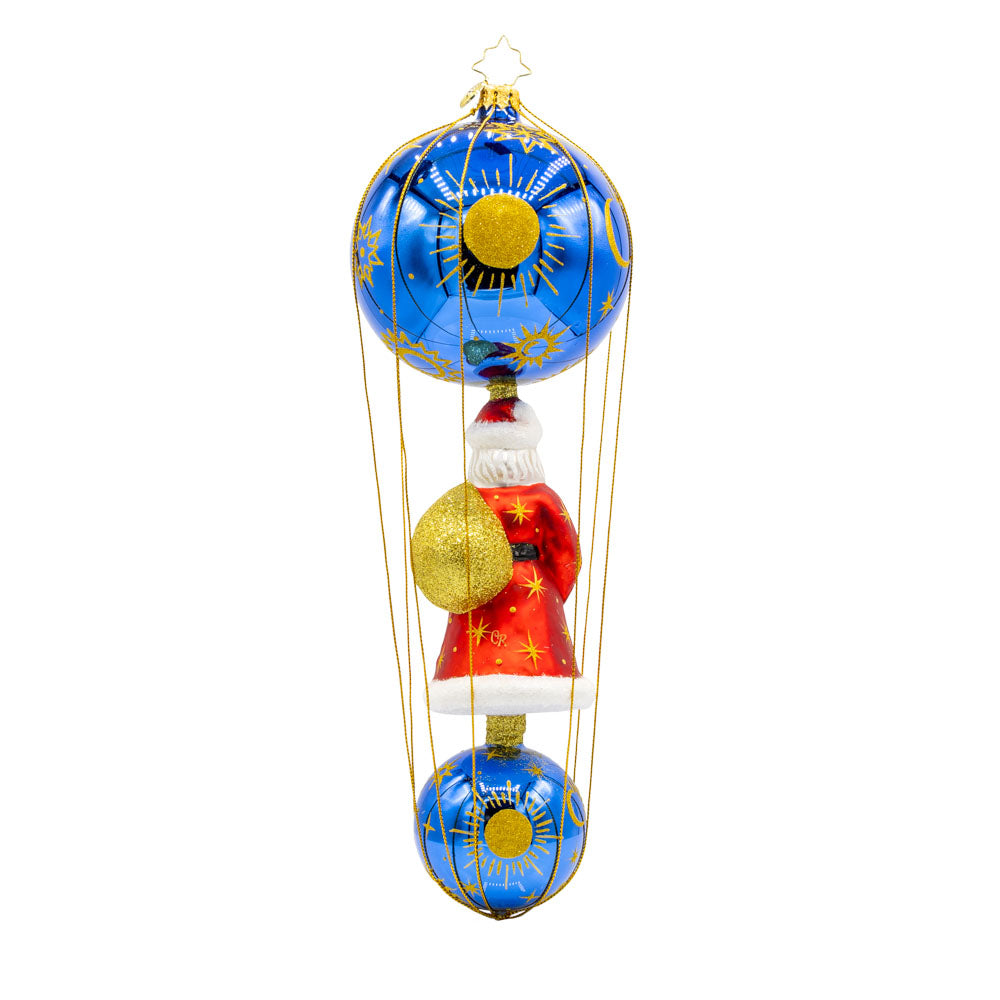 Santa soaring among the stars in a celestial-themed hot air balloon. With its shimmering blue and gold celestial pattern, vibrant red satin Santa, and glittering gift bag, this ornament is a dazzling symbol of holiday wonder and elegance. View of back.