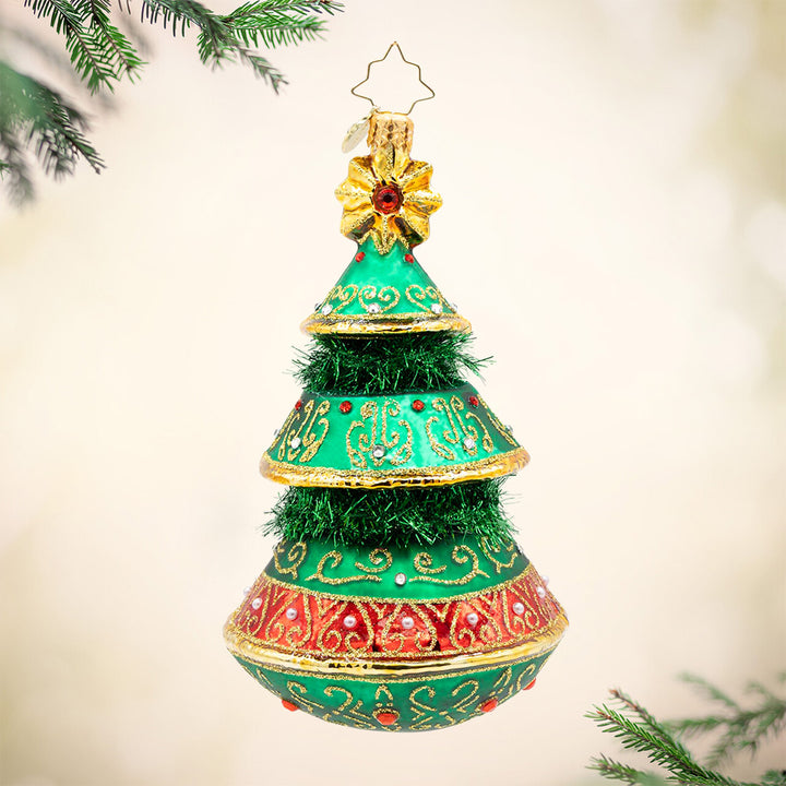 The Gilded Evergreen.  Tree ornament adorned with green tinsel, red and white gems, and gold detailing. View of front