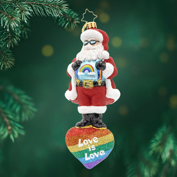 Love Wins Santa. Ornament of Santa in his red suit and a blue shirt with rainbow, with Santa standing on top of a rainbow heart with the phrase "love is love." View of front