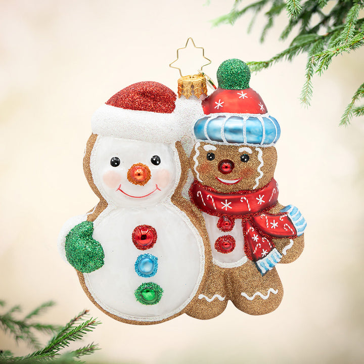 Deck the Dough. Ornament of a gingerbread man, in a red and blue matching scarf and hat, next to a giant snowman cookie. View of front