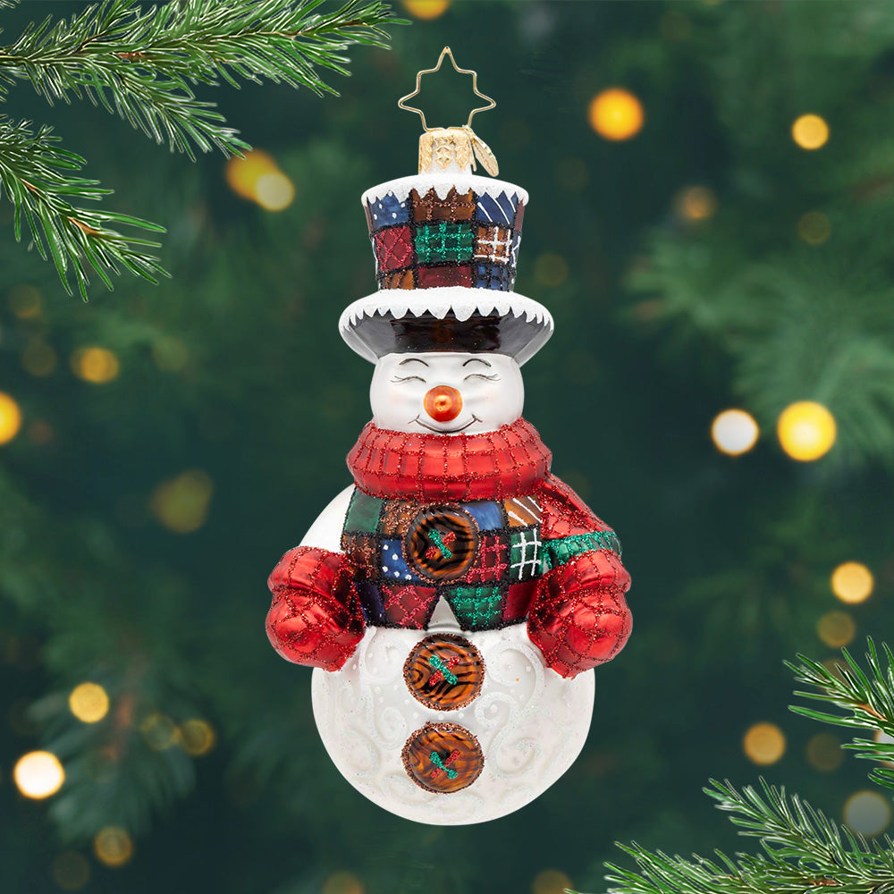 Plaid Tidings. Snowman ornament dressed in red, blue, green and brown vest with matching hat and a red matching scarf and mittens. View of front