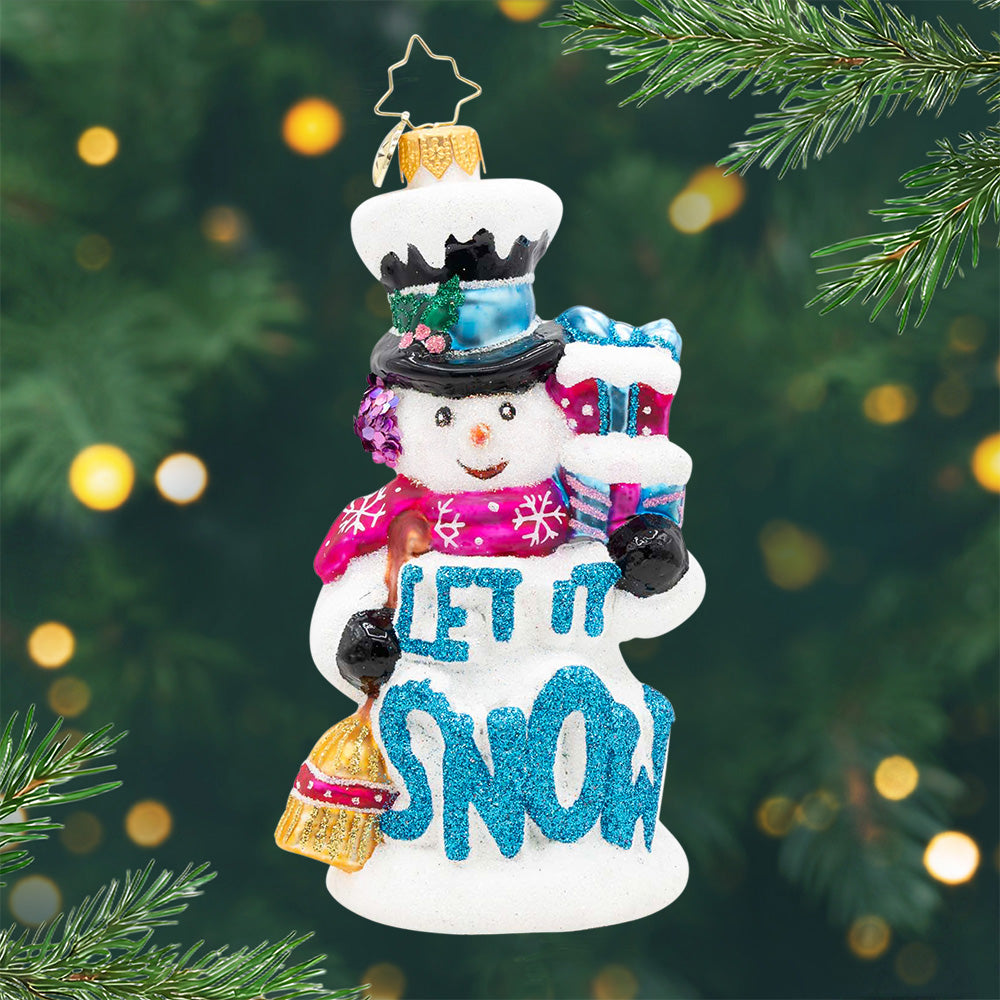 Let It Snowman! Ornament of a snowman holding two presents in the colors pink and blue in one had and in the other a broom, with the phrase "Let It Snow" in blue on the front. View of front