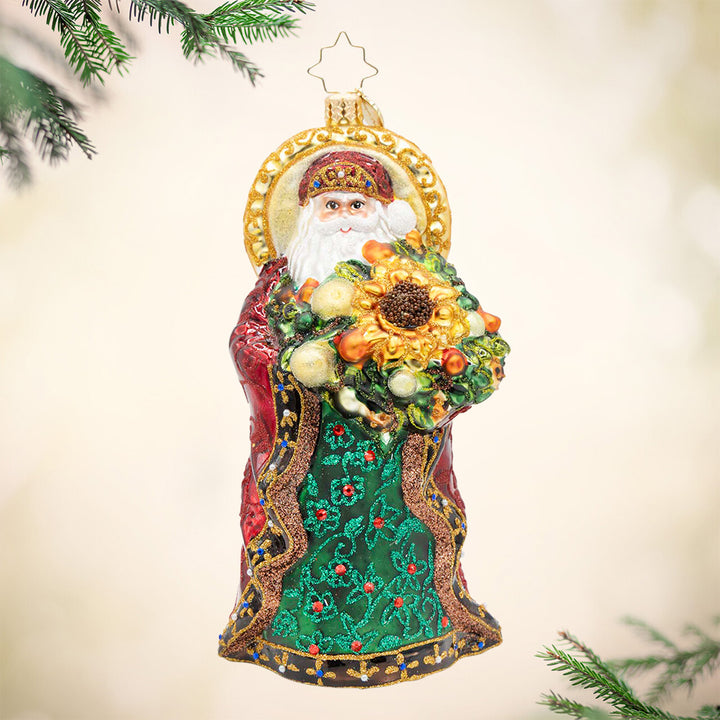 Regal Radiance. Santa dressed in a sparkly retailed red and green robe and holding a bouquet of flowers with a giant sunflower in the middle. View of front