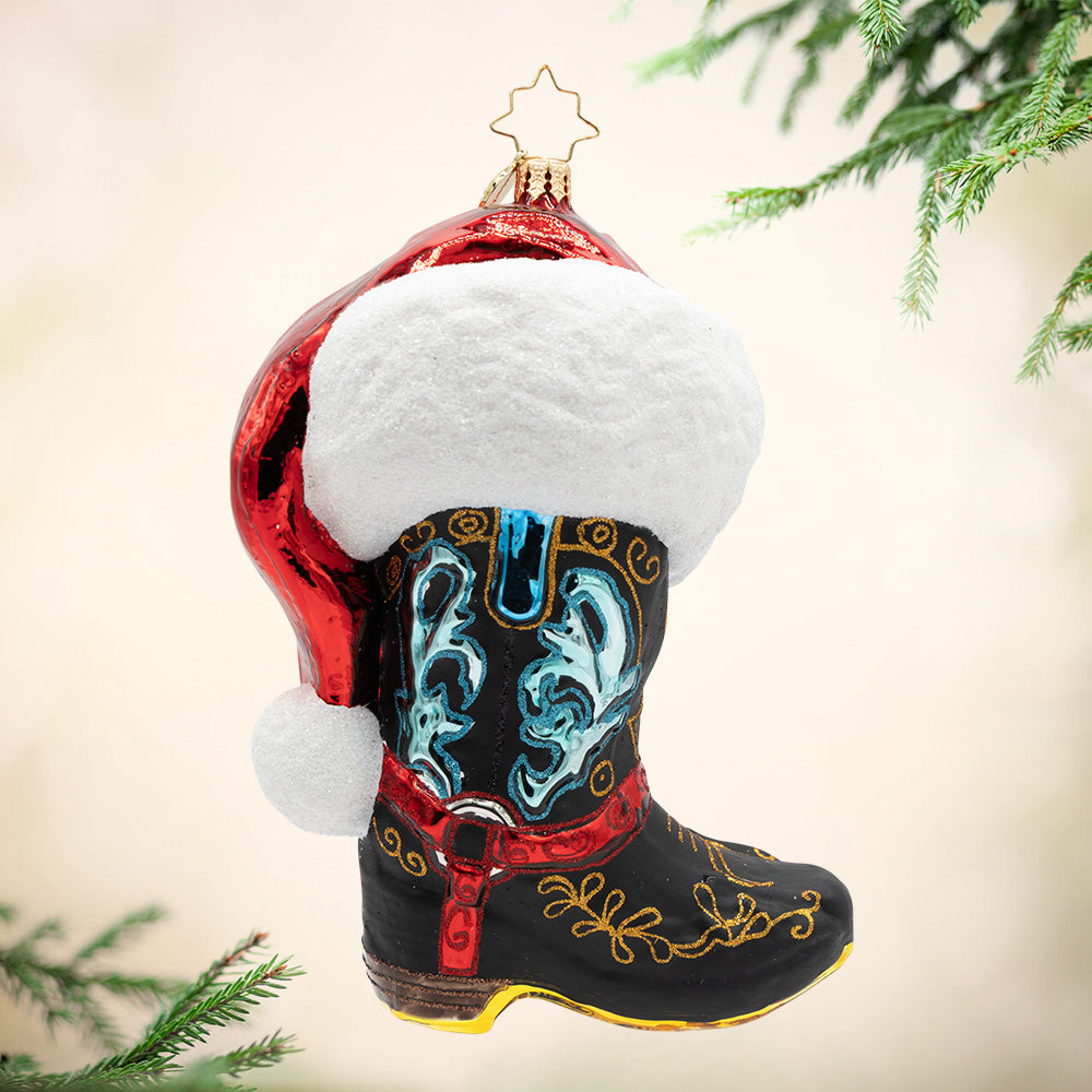 Howdy Holidays. Ornament of a black cowboy hat with red, gold, and blue details and a red Santa hat on top. View of front