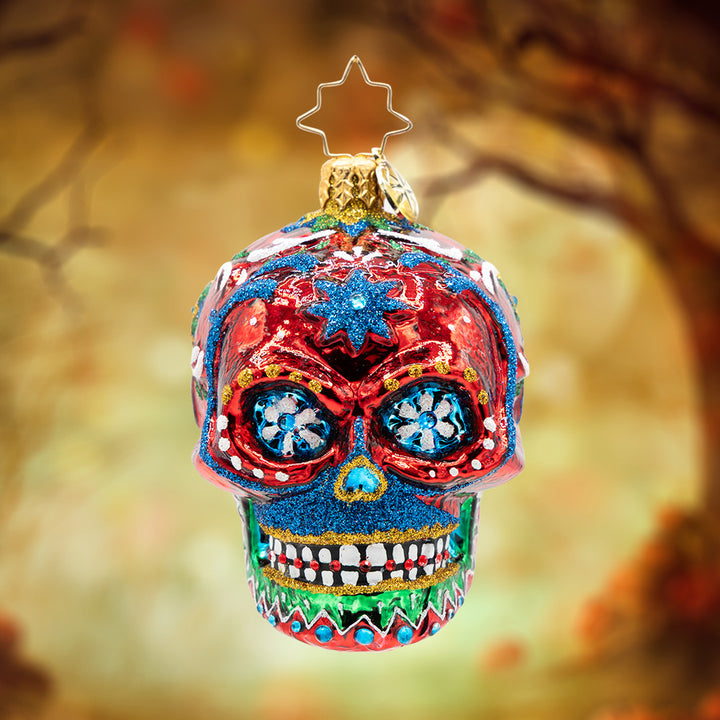 Calavera Fiesta Gem. A skull ornament in vibrant colors of red, green, and blue with gems. View of front