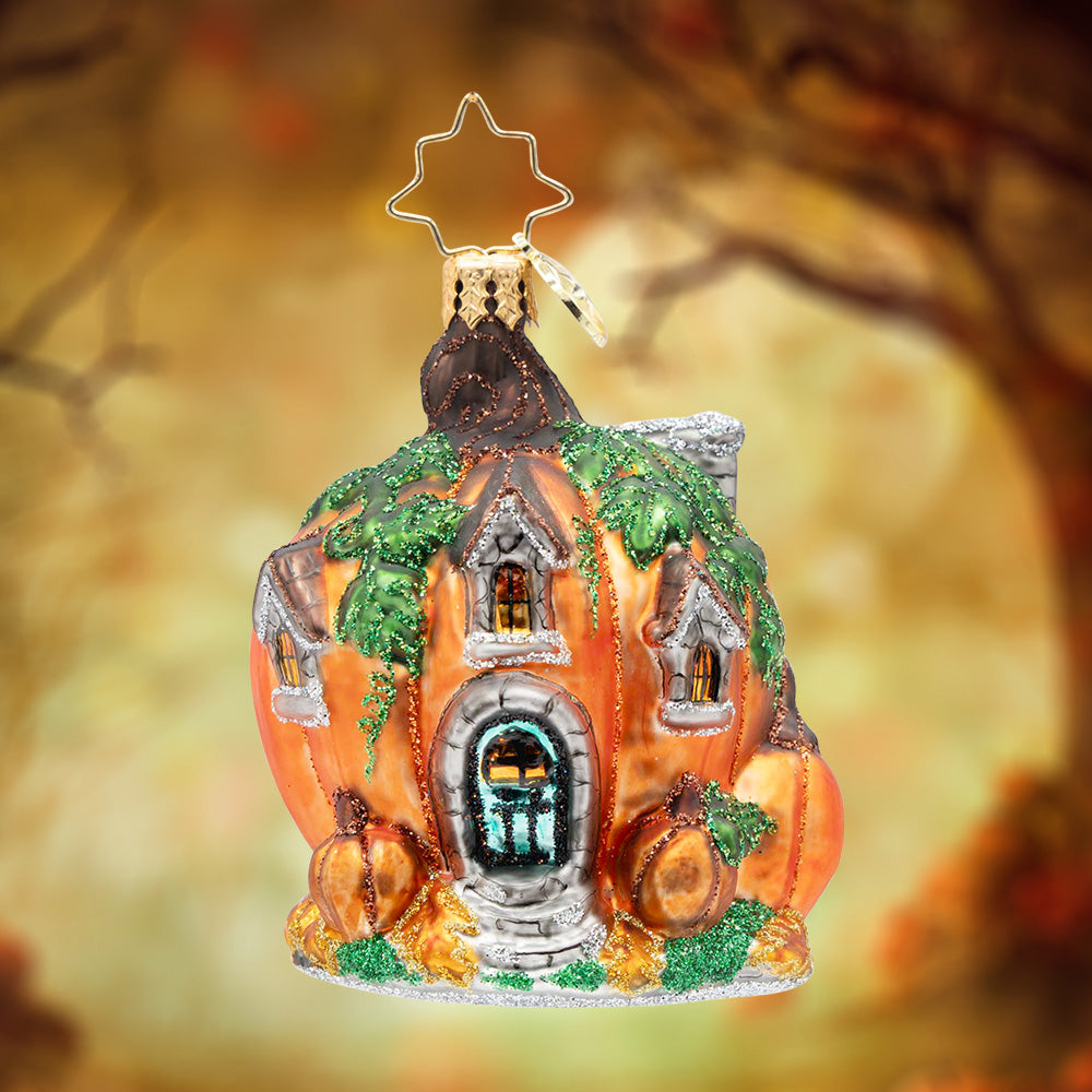 Pumpkin Patch Abode Gem. A house ornament in the shape of a pumpkin with three silver windows, green vines draping over the pumpkin and 3 more pumpkins in front. View of front