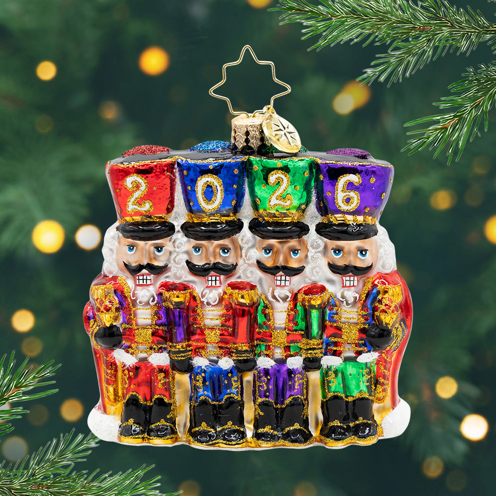 2026 Marching Guardians Gem. Ornament of four nutcrackers in the colors of red, purple, green, blue, and gold detailing with their hats spelling the year 2026. View of front