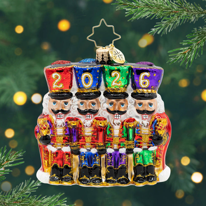 2026 Marching Guardians Gem. Ornament of four nutcrackers in the colors of red, purple, green, blue, and gold detailing with their hats spelling the year 2026. View of front