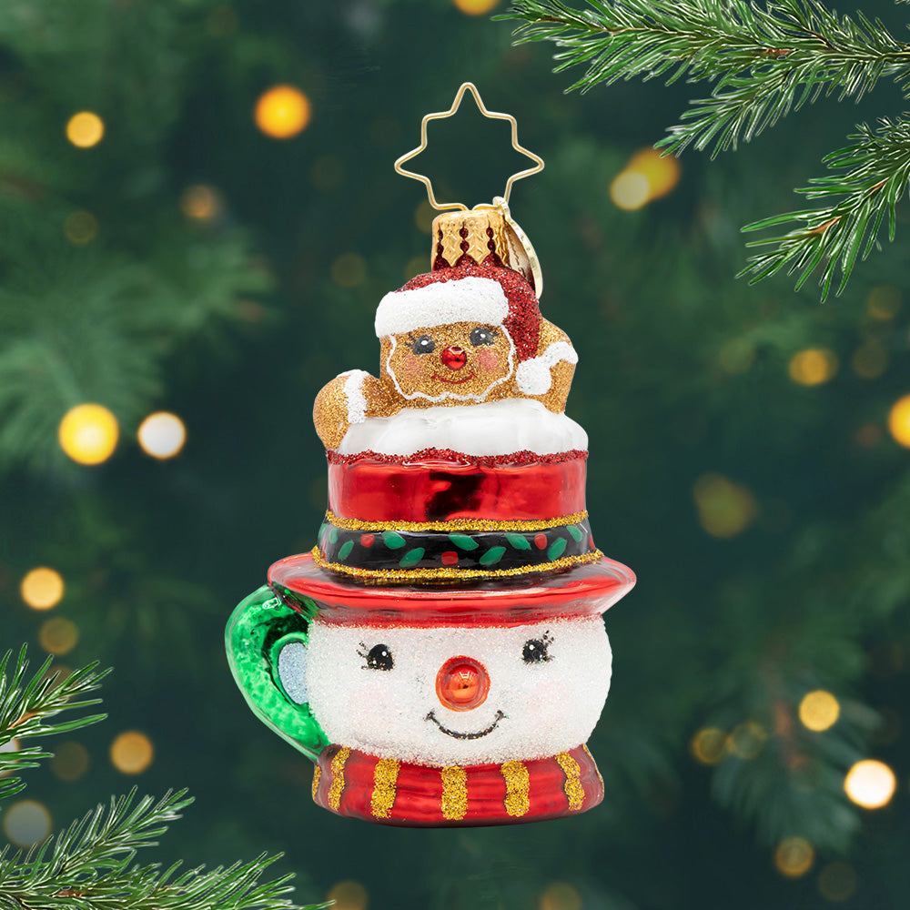 Hot Cocoa Delight Gem. Ornament of a sparkly brown gingerbread man popping out of a snowman mug in a red top hat. View of front